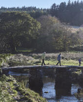 Gente caminando por un puente de piedra sobre un río
