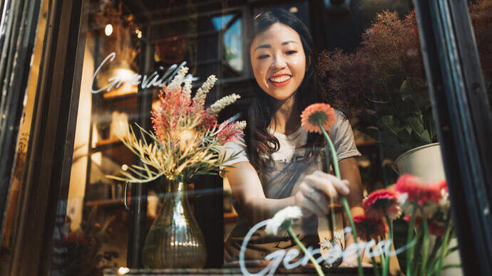 Asian young florist working on the arrangement of flowers for her shop.