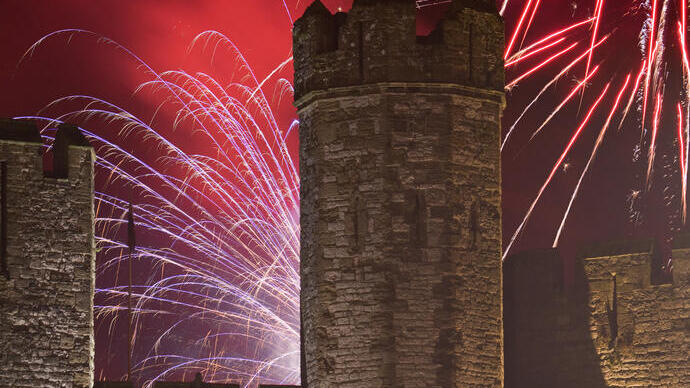 Fireworks exploding over castle turrets and walls at night