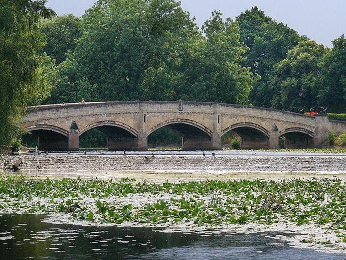 People walking across a bridge in Abbey Park, Leicester