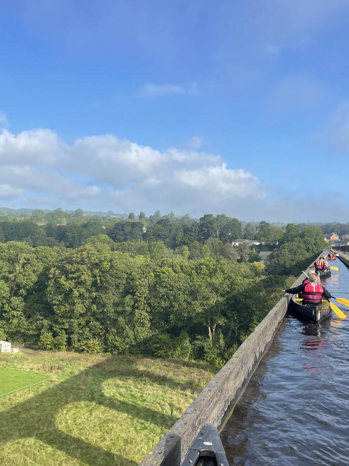 Un groupe pagayant en kayak sous un viaduc avec vue panoramique sur le parc national de Snowdonia/Eryri