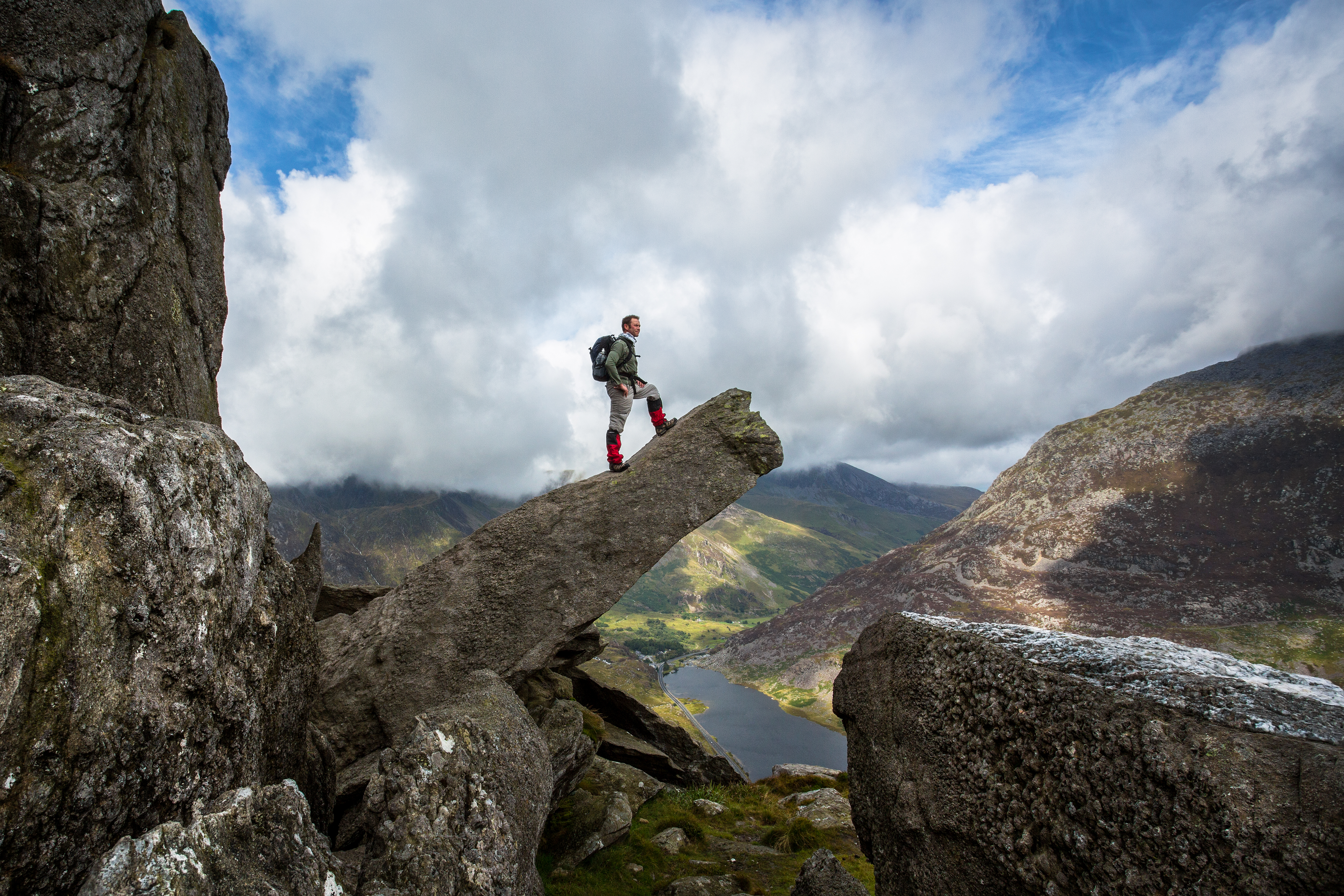 Man standing on a protruding pinnacle rock formation and looking at the view