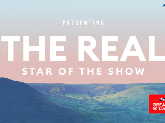 A cinematic destination ad featuring a paraglider soaring over hills in Great Britain.