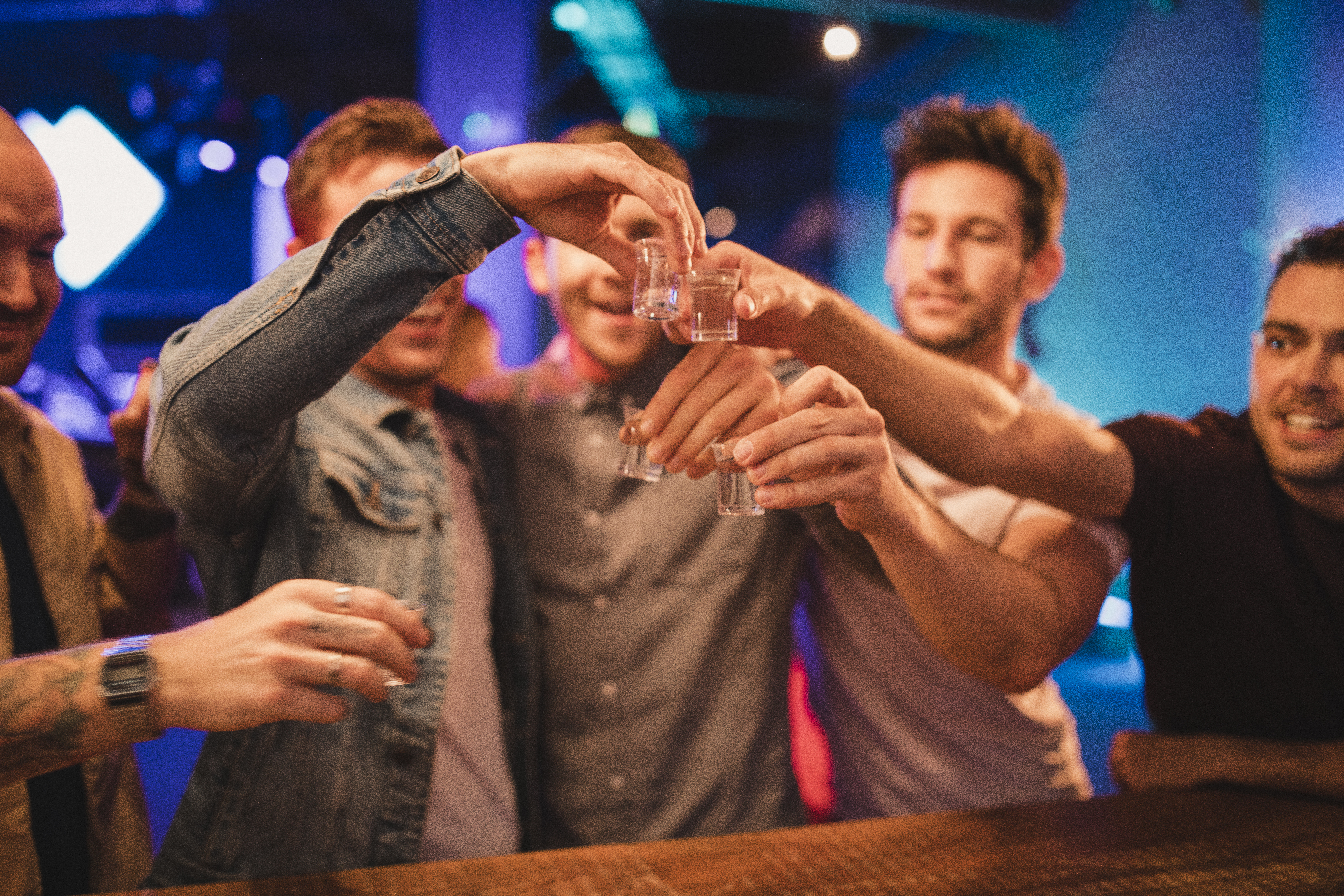 Group of men on a night out toasting their shots before drinking them, celebrating New Year