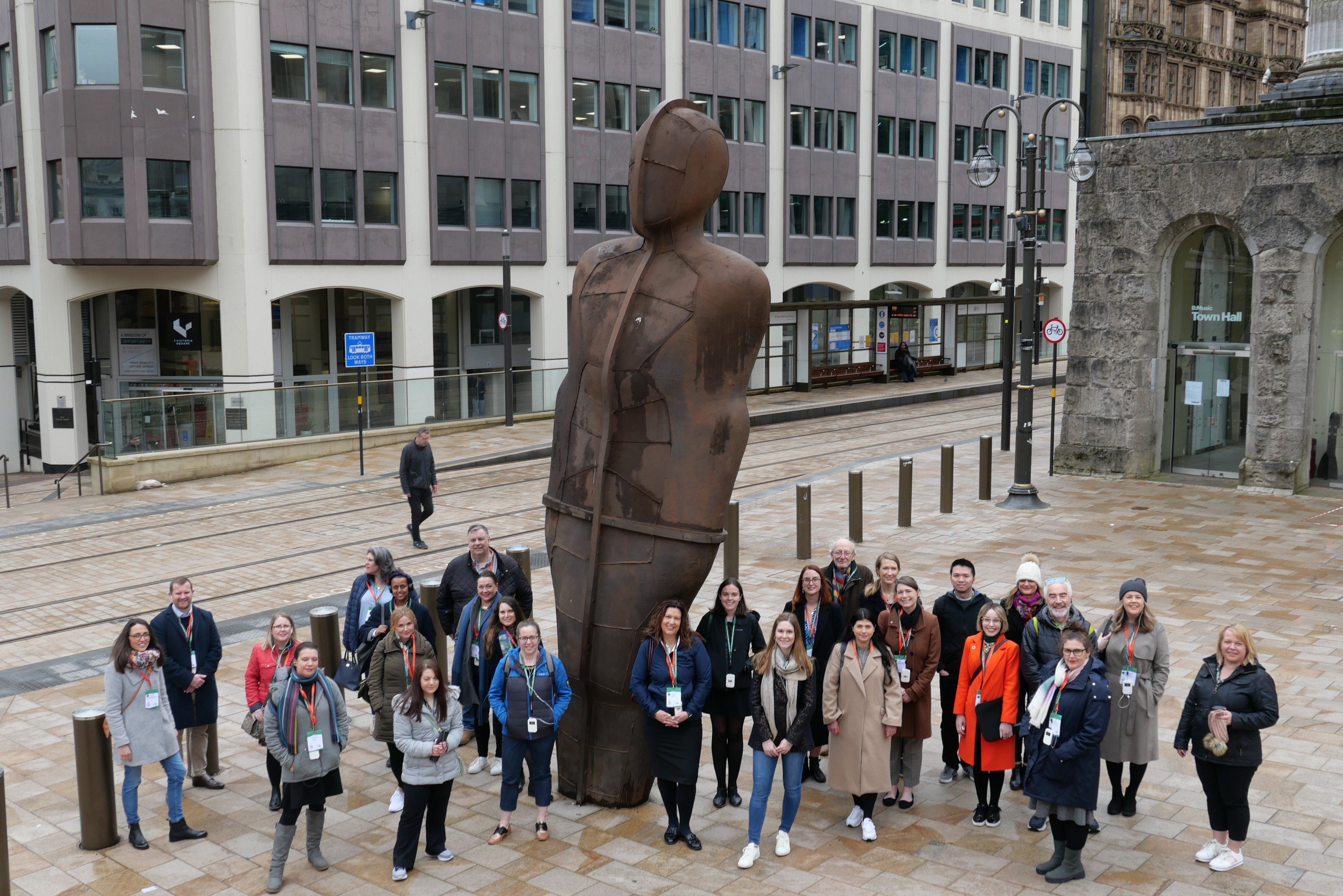 A tour group posing alongside a statue in Birmingham as part of a Positively Birmingham walking tour