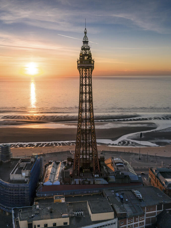 Tall tower near a beach at sunset. Sun reflecting in sea