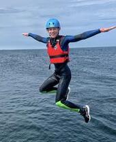 Una donna con equipaggiamento di sicurezza che si tuffa da una barca in mare - KA Adventure Sports