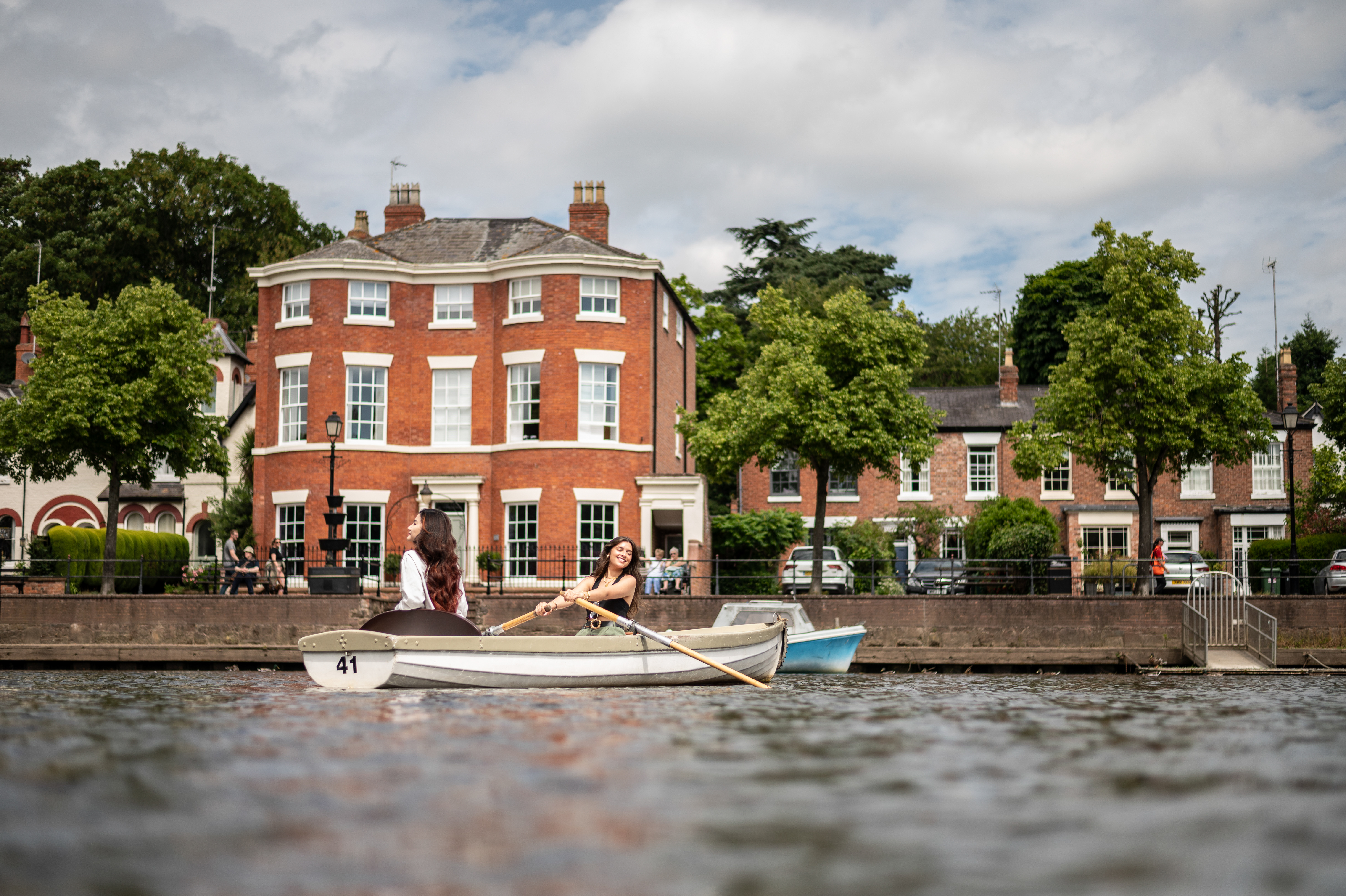 Two women sit in a row boat in a City