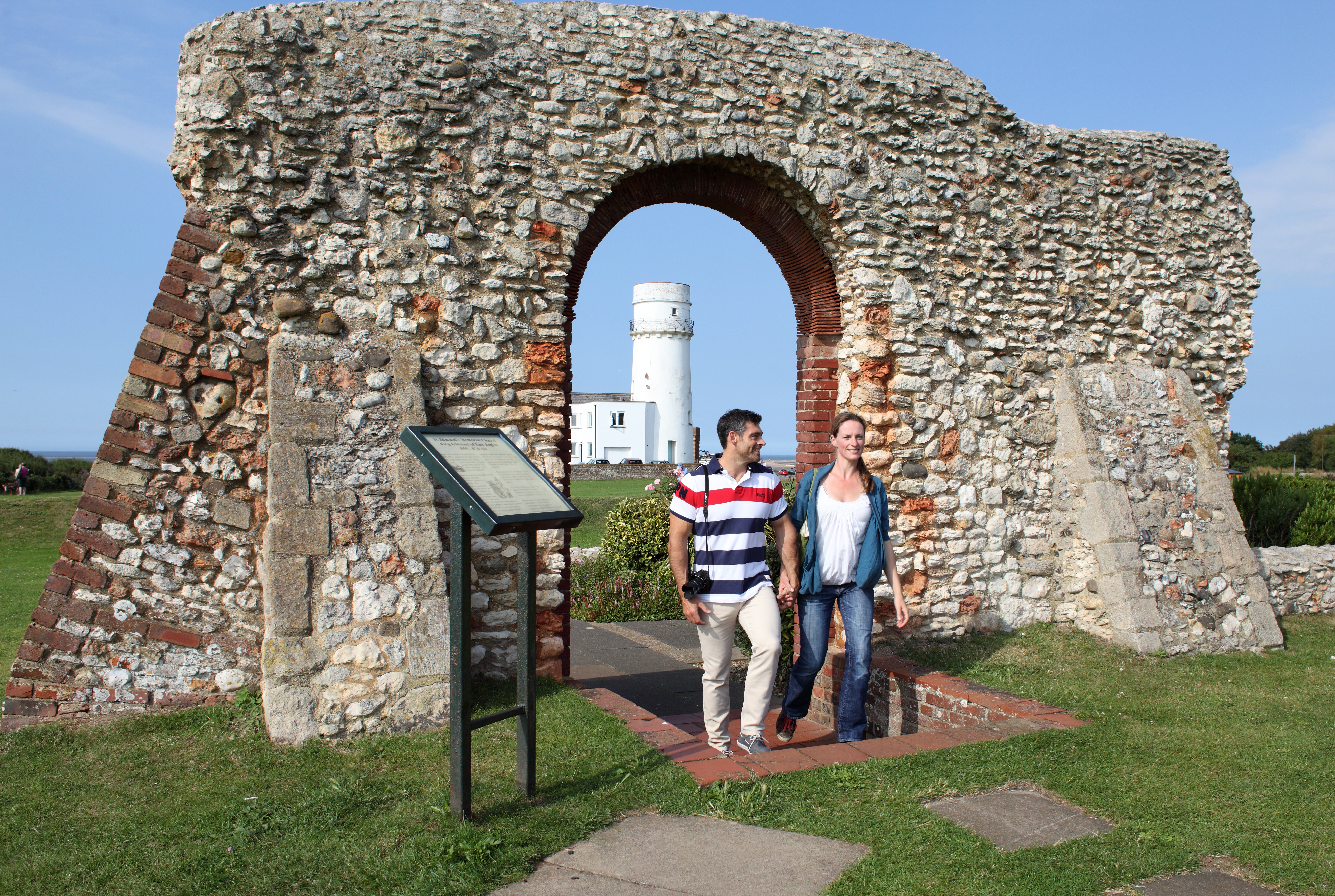 Two people stood outside Hunstanton chapel with the lighthouse in the background