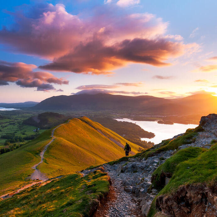 Hiker walking along a path on a mountain ridge at sunrise