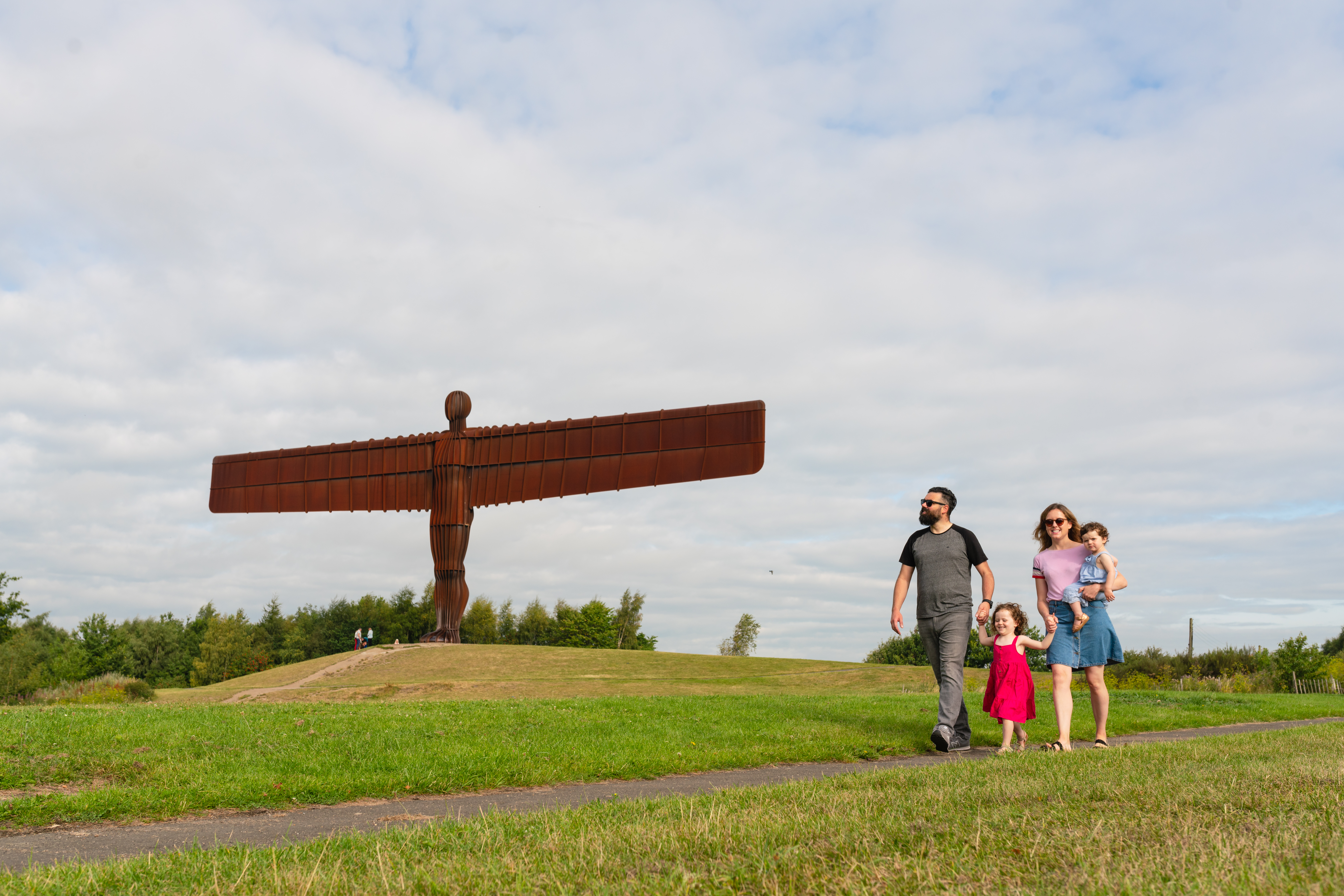 Eine Familie spaziert vor dem ikonischen Angel of the North, der sich südlich von Newcastle Gateshead befindet