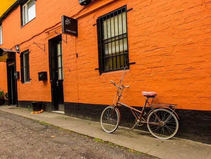 Bicicleta aparcada frente a una joyería con pared pintada de naranja en Hidden Lane, Glasgow.