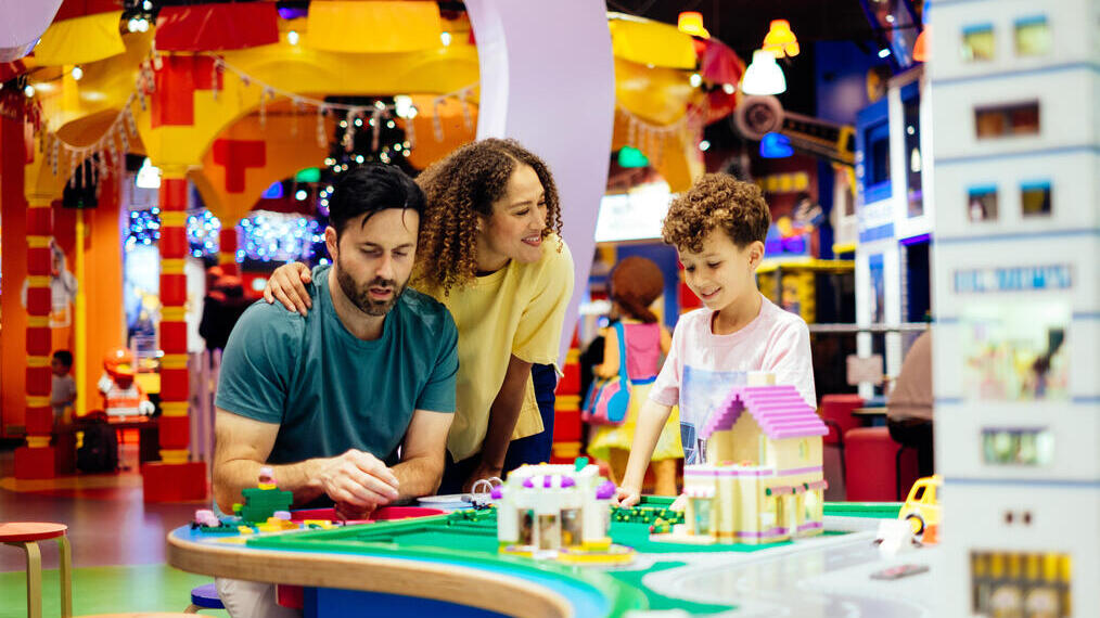 Mother, father and son laughing whilst playing with Lego