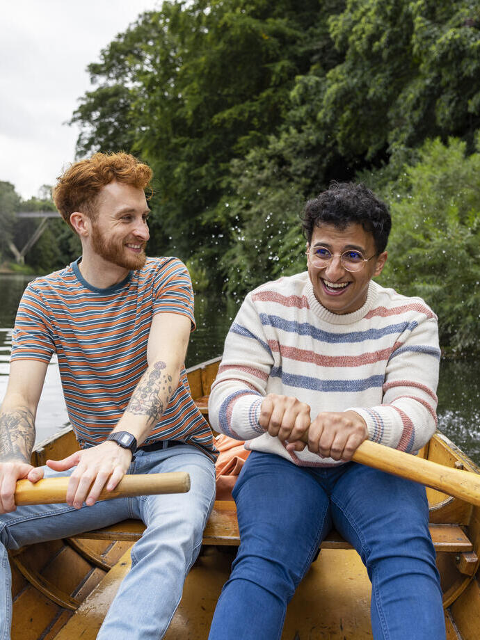 A male couple sitting in a rowboat, rowing together