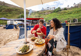 Couple eating food at a beach café and restaurant with the sea in the background