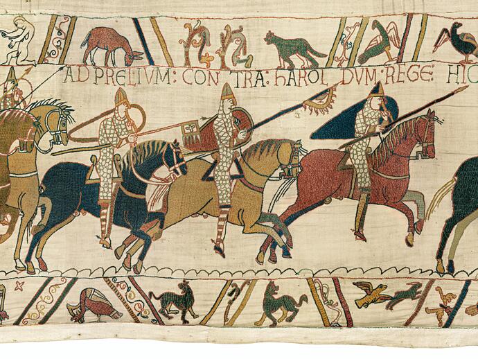 Medieval tapestry showing armored horse riders in battle, with animals and Latin text above and below the main scene.