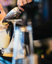 Bartender preparing a cocktail in a large glass