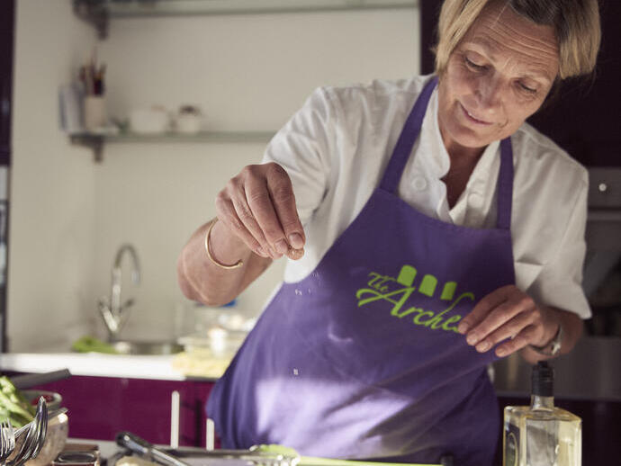 Blonde Frau mit lila Schürze, die in der Küche Essen zubereitet