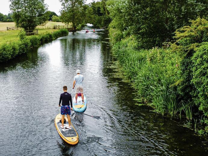 Two men paddle boarding on a river
