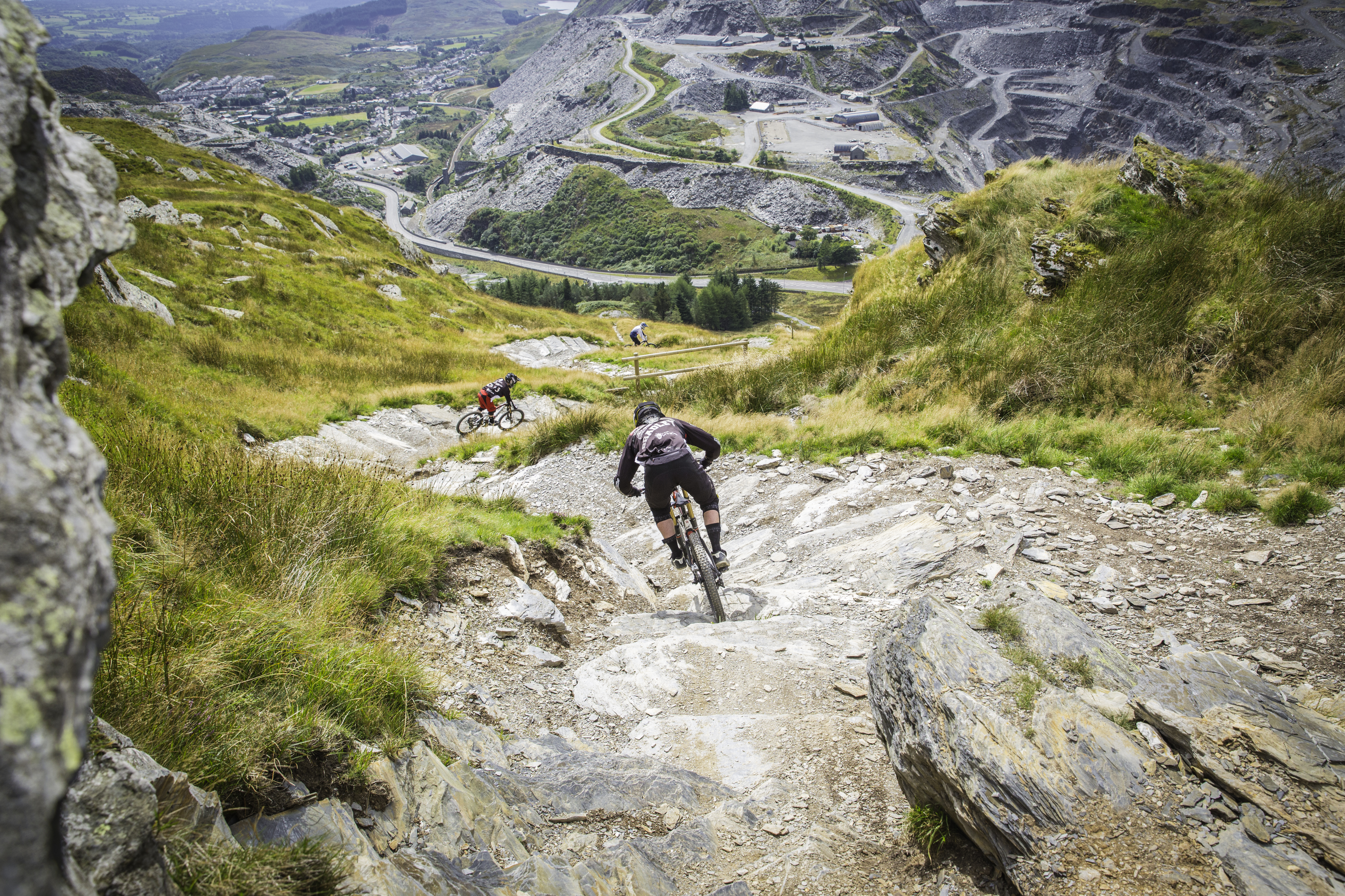 People mountain biking down a steep hill.