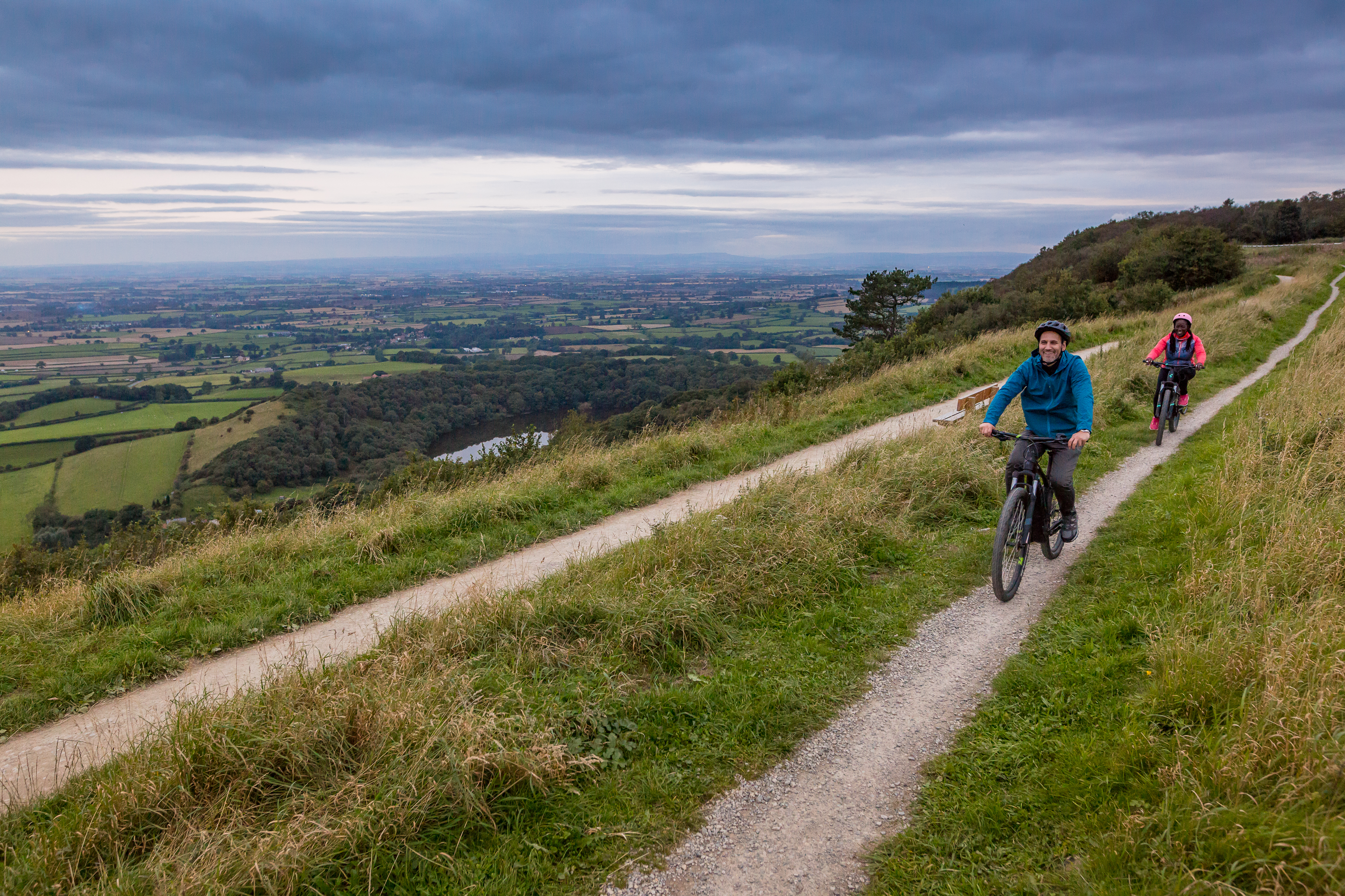 Man and woman riding bikes along a path on a ridge