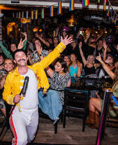 Freddy Mercury impersonator on stage in front of a crowd at Katie's Bar and Kitchen in Glasgow, Scotland