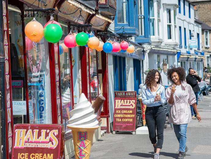 Two women walk down a street with ice creams