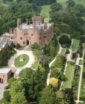 Aerial shot of a castle surrounded by acres of landscaped gardens.