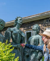 A girl putting flowers into the hands of a statue