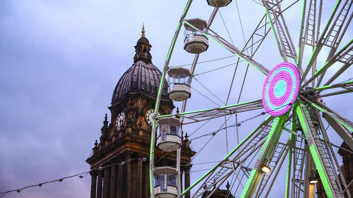 Looking up at clock tower and a Ferris wheel at dusk