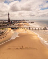 Vista panorámica de una playa de arena con un muelle y una torre.