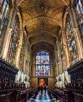 Innenansicht der Kings College Chapel in Cambridge mit Gewölbedecke und riesigen Holzvertäfelungen, darüber Buntglasfenster.