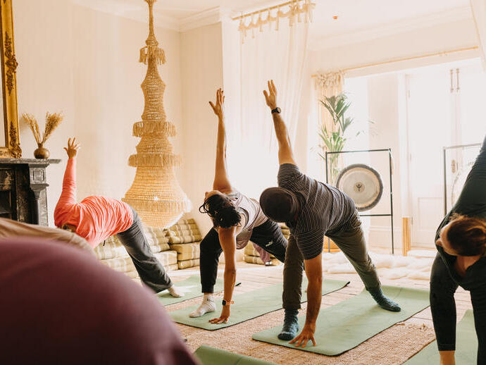 Quattro persone praticano yoga su tappetini durante un ritiro benessere