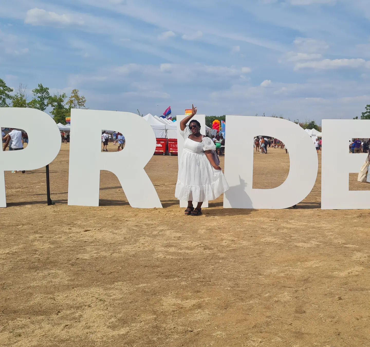 Frau in weißem Kleid vor dem Schild „UK Black Pride”