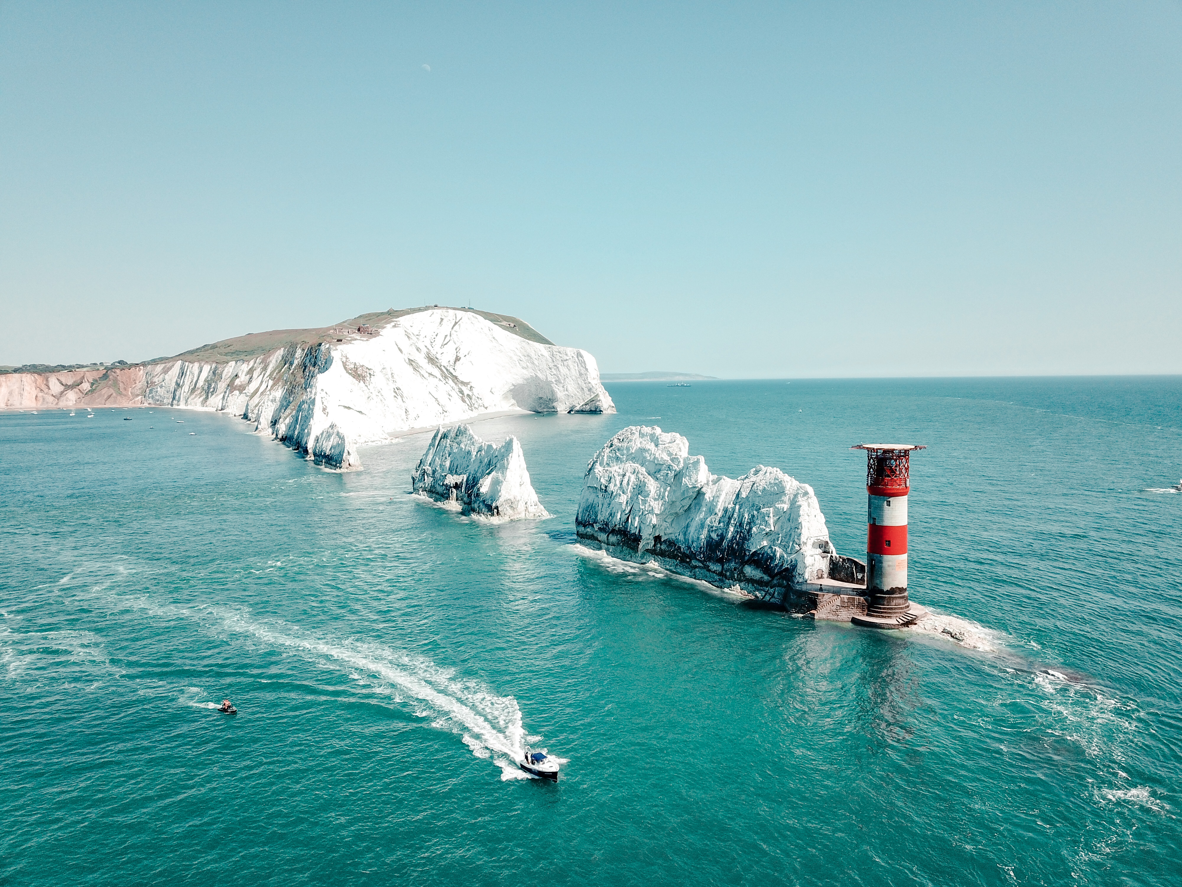 Hohe Kreideformationen in einer Reihe, die sich von den Klippen des Festlandes bis zu einem Leuchtturm erstrecken