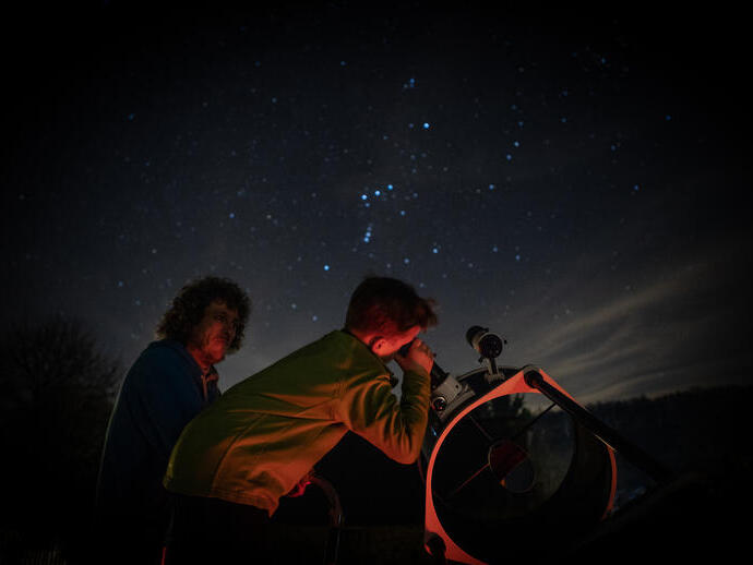 Child stargazing through telescope