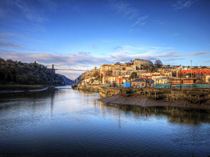 A city on the banks of a river with a large bridge in the distance