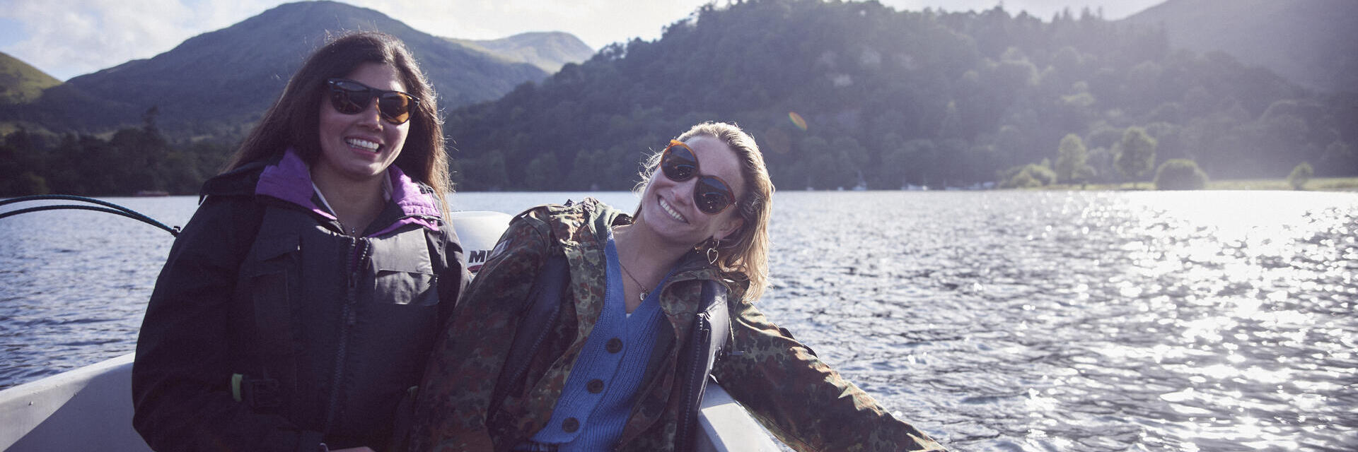 Two women wearing sunglasses on a boat on the lake