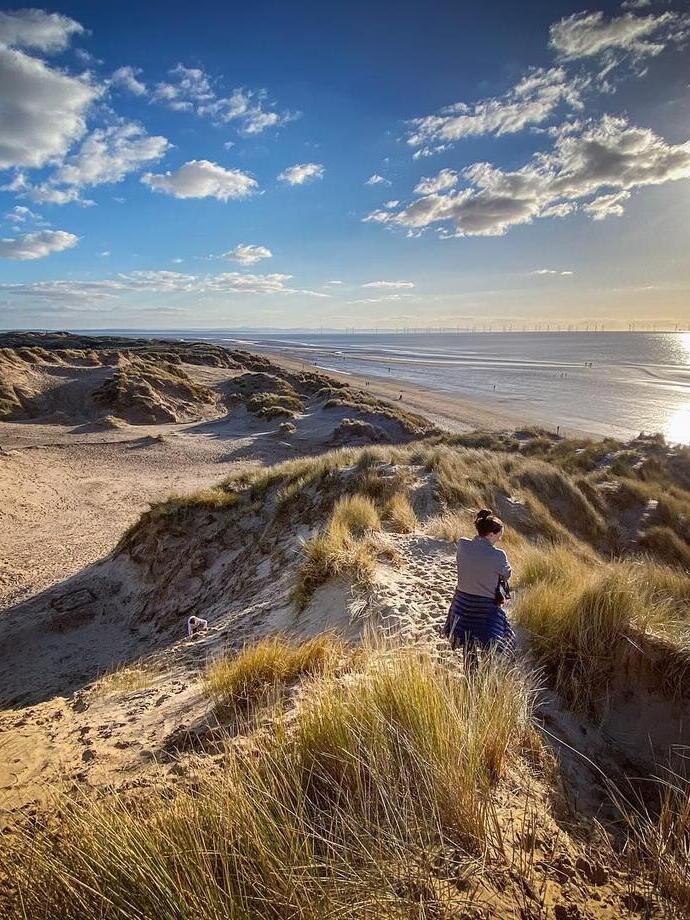 Woman walking along sand dunes at Formby beach