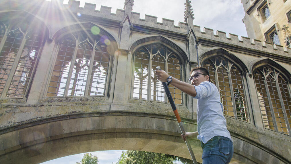 Man punting beneath a bridge