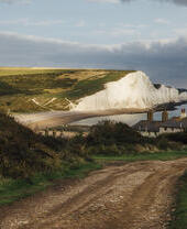 Ferienhäuser an der Küste mit Meer und weißen Klippen im Hintergrund