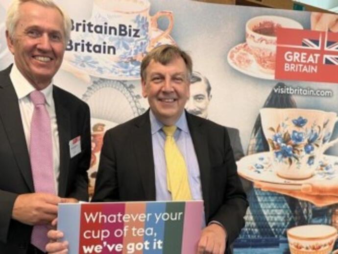 Nick De Bois posando delante de material promocional de VisitBritain