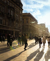 Shoppers walking along a sunny busy shopping street.