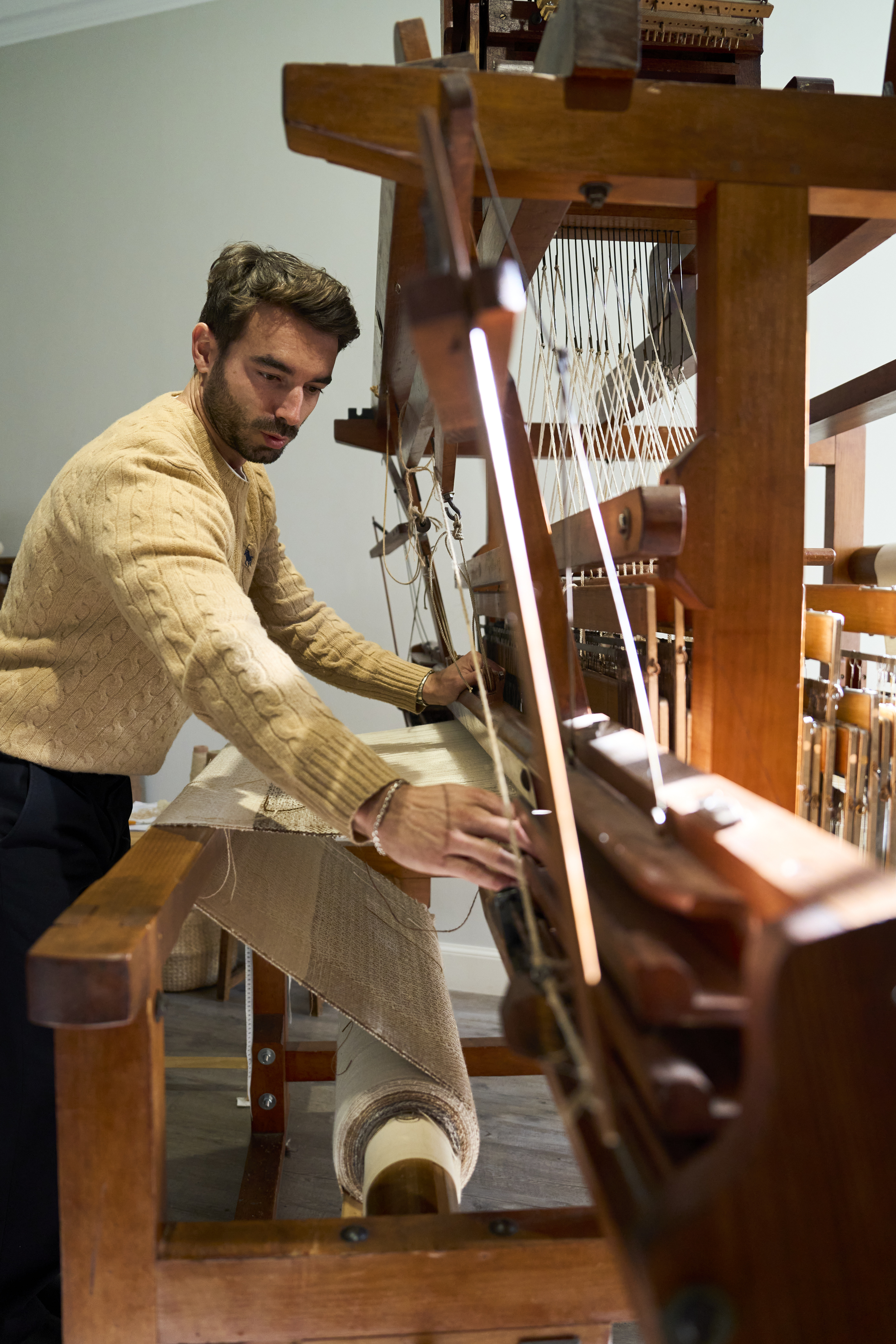 A person weaving fabric on a traditional wooden loom.