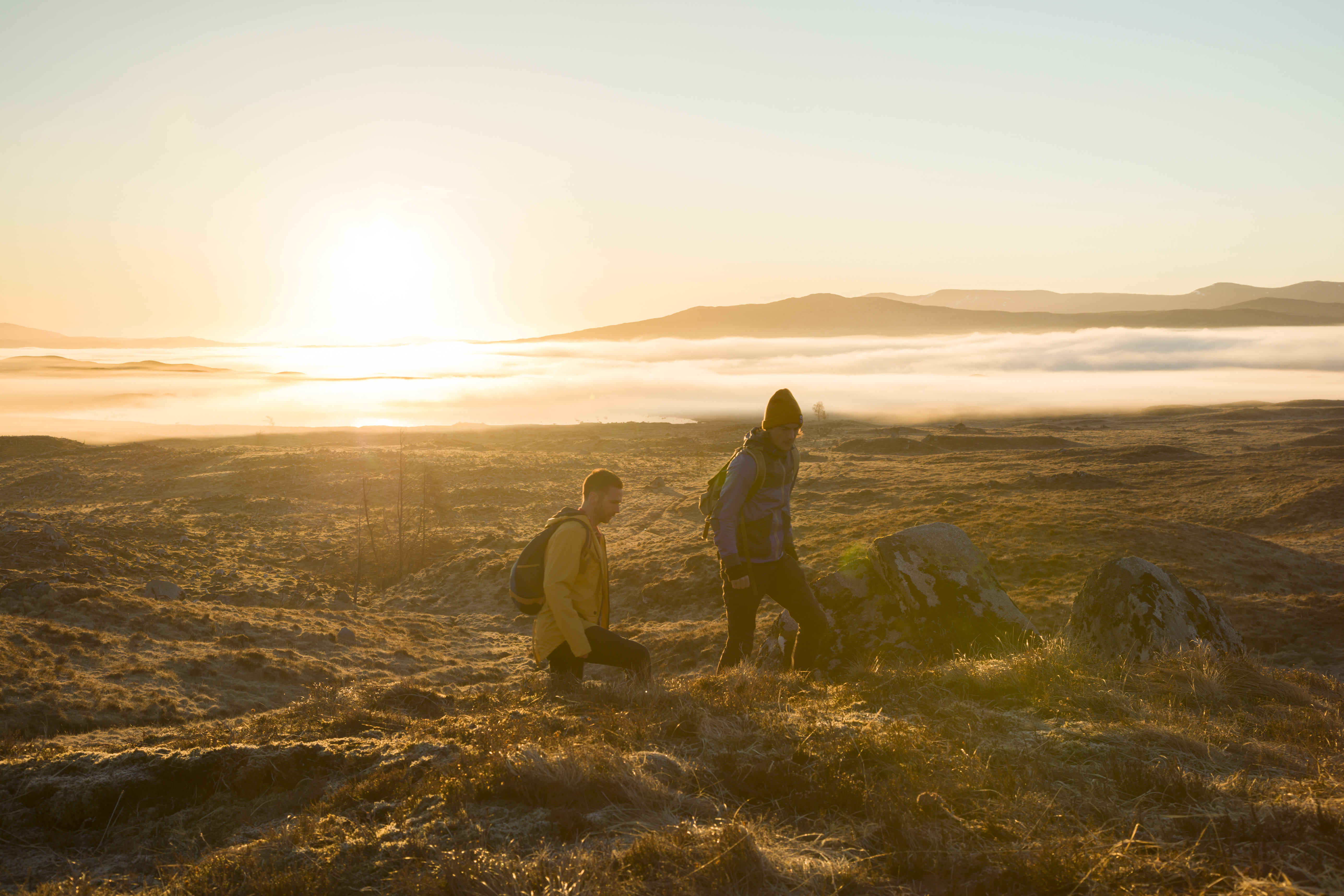 Zwei Männer wandern bei Sonnenuntergang im Hochland. Strahlendes Sonnenlicht