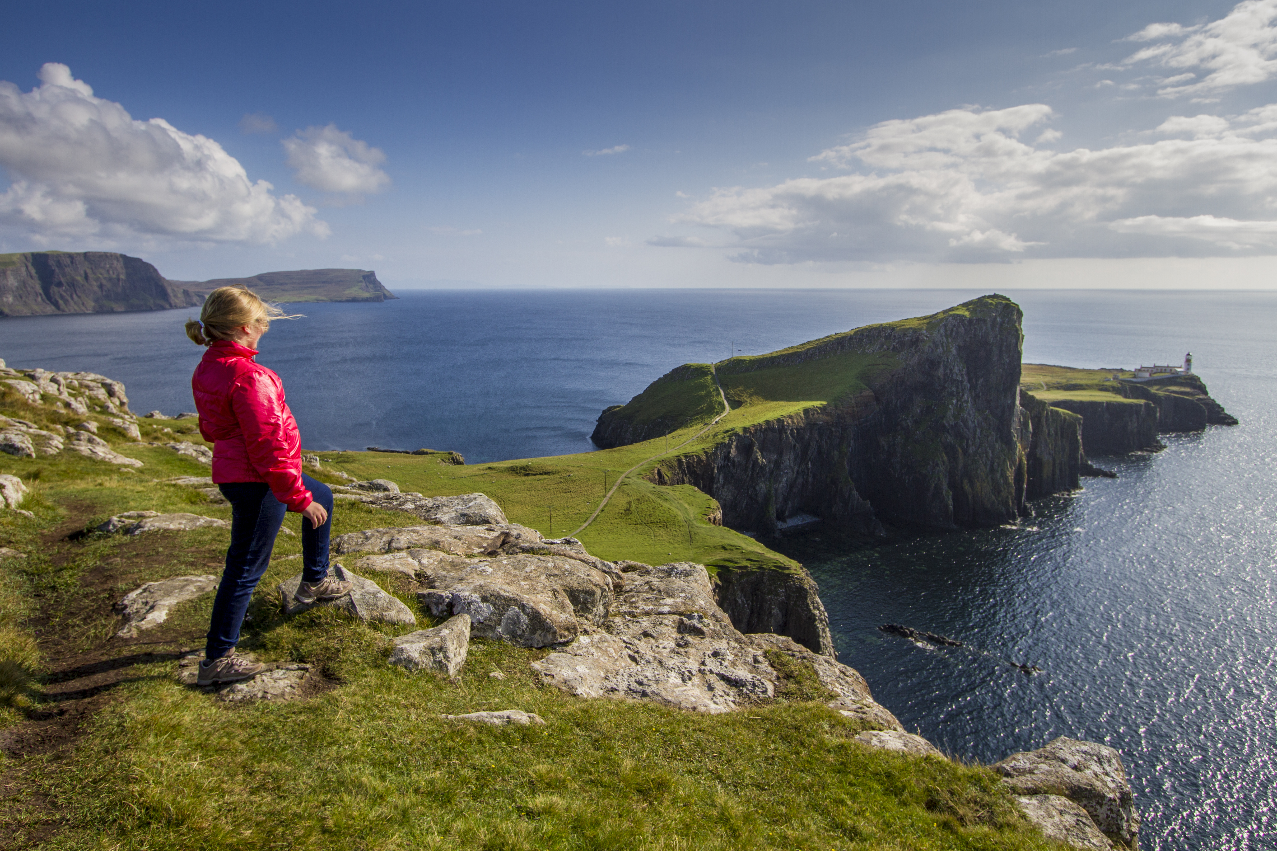Young walker looking at the view of the ocean from a cliff edge peninsula.