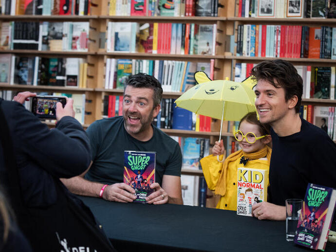 Two men holding books and posing with a child