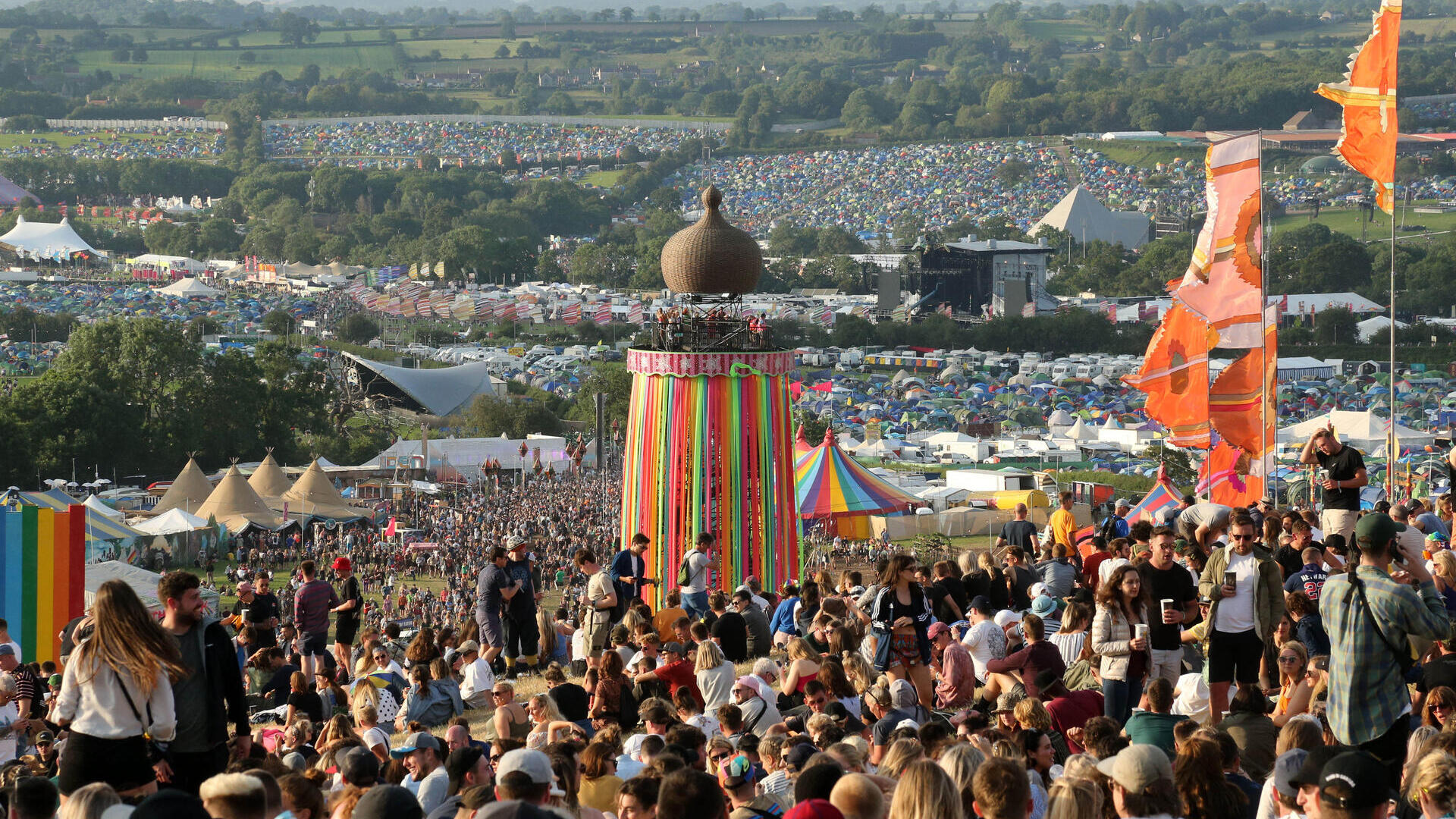 Crowd at Glastonbury Festival sitting on a hill during the day