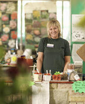 Female Garden Centre worker in an apron behind a till.