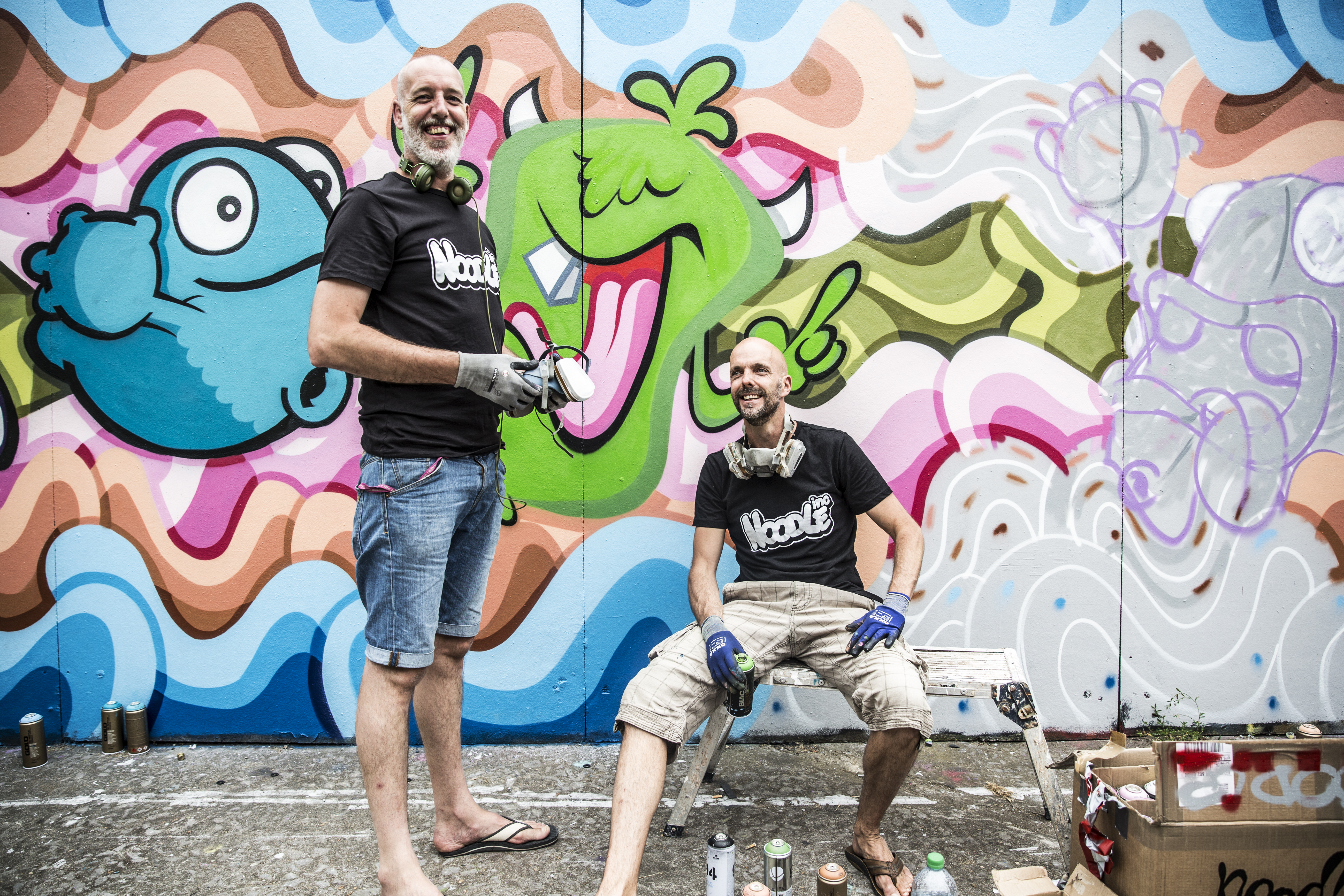 Street artists with paint cans near colourful artwork